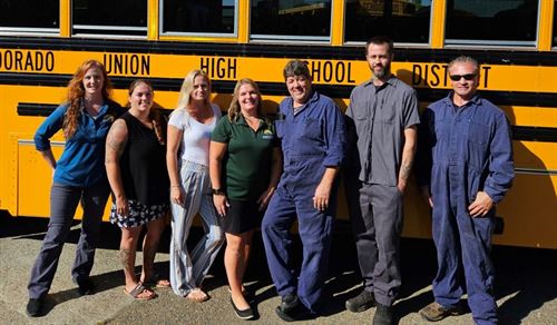 7  people standing in front of a school bus